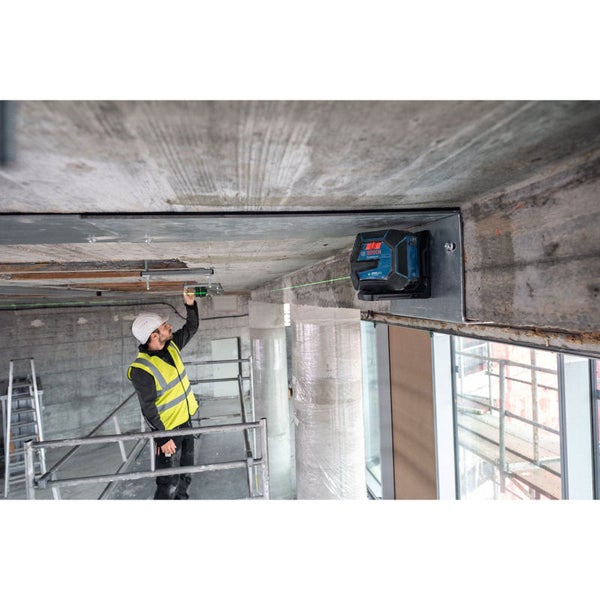 Ein Bauarbeiter justiert einen Linienlaser an einer Decke auf einer Baustelle.