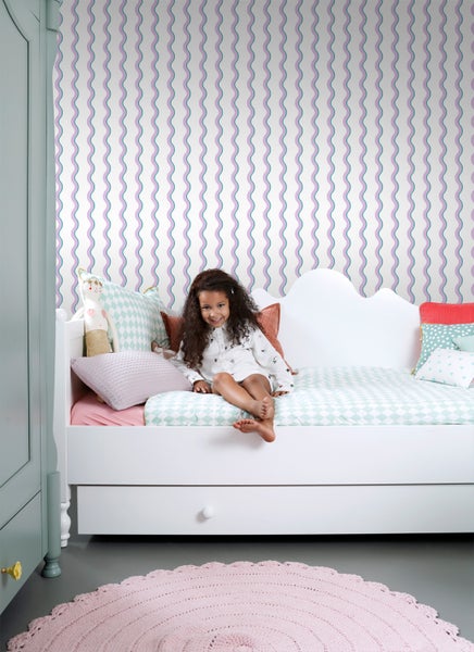 Mädchenzimmer mit weißem Bett, Mustertapete und rundem Teppich