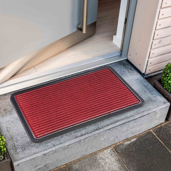 Rote Fußmatte mit Bordüre vor einer geöffneten Tür