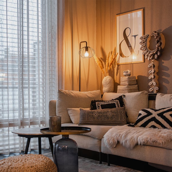 Wohnzimmer mit Couch, Kissen, Tisch, Stehlampe und Dekoration