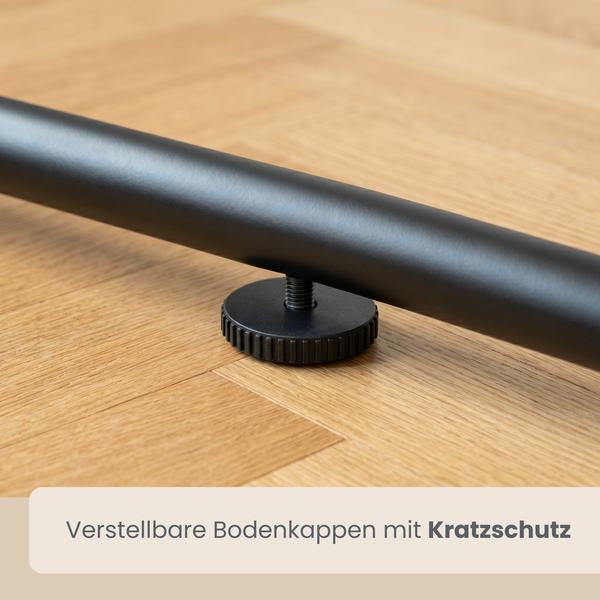 Detailansicht einer verstellbaren schwarzen Bodenkappe mit Kratzschutz an einem schwarzen Metallgestell auf Holzboden.