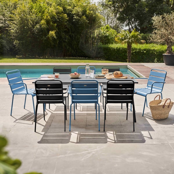 Modernes Gartenmöbel-Set mit grauem Tisch und blauen sowie schwarzen Stühlen auf einer Terrasse am Pool im sonnigen Garten.