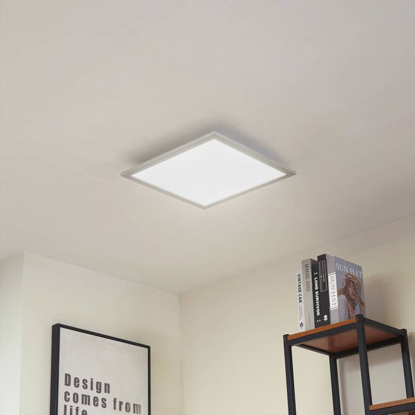 Quadratisches LED-Panel als flache Deckenleuchte in einem modern eingerichteten Innenraum mit Regal und Bild.