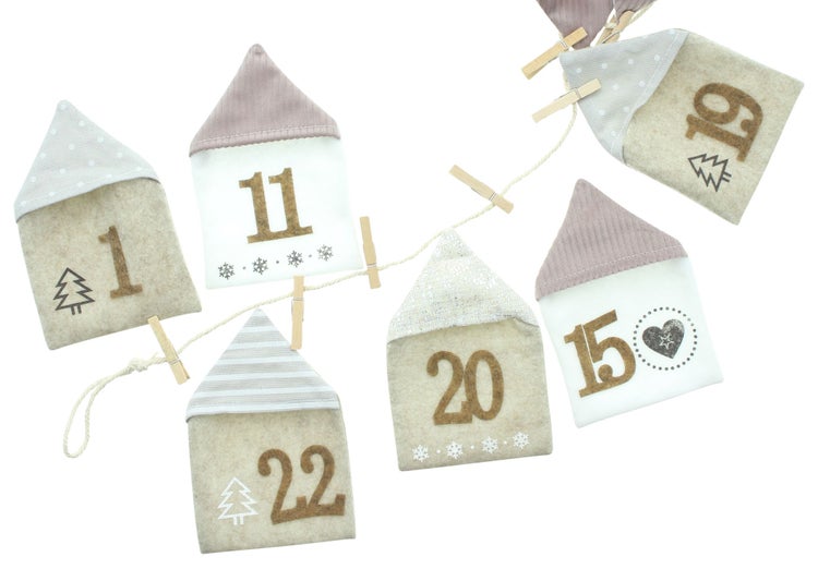 Dekorativer Adventskalender mit Hausmotiven und Zahlen an einer Schnur befestigt.
