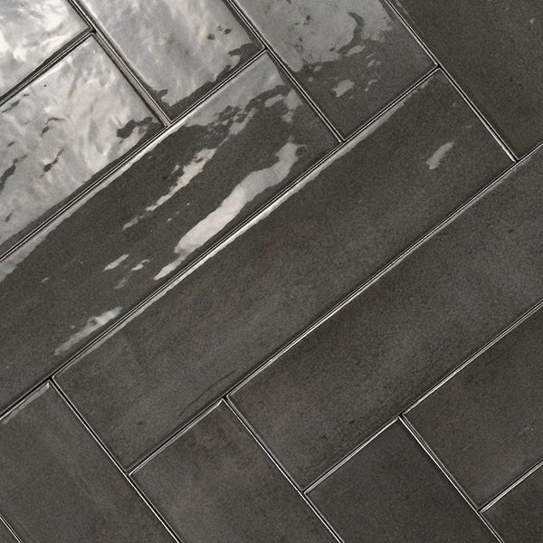 Dunkle Wandfliesen im Fischgrätmuster mit glänzender Oberfläche für Wohnräume.