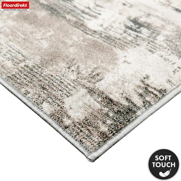 Detailansicht eines Teppichs mit abstraktem Muster und der Kennzeichnung weiche Haptik.
