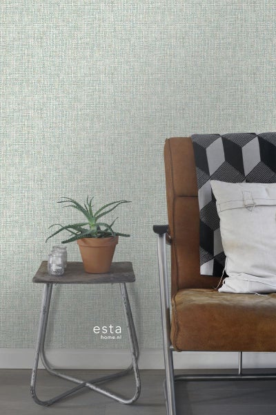 Szene mit Textiltapete, kleinem Beistelltisch mit Pflanze und Sessel.