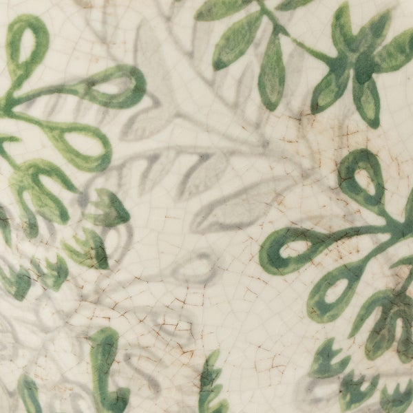 Nahaufnahme einer Keramikoberfläche mit Craquelé-Glasur und Blattmuster in Grün und Grau.