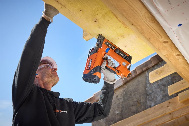 Ein Handwerker nutzt einen Paslode Nagler, um einen Holzbalken an einem Dachstuhl zu befestigen.