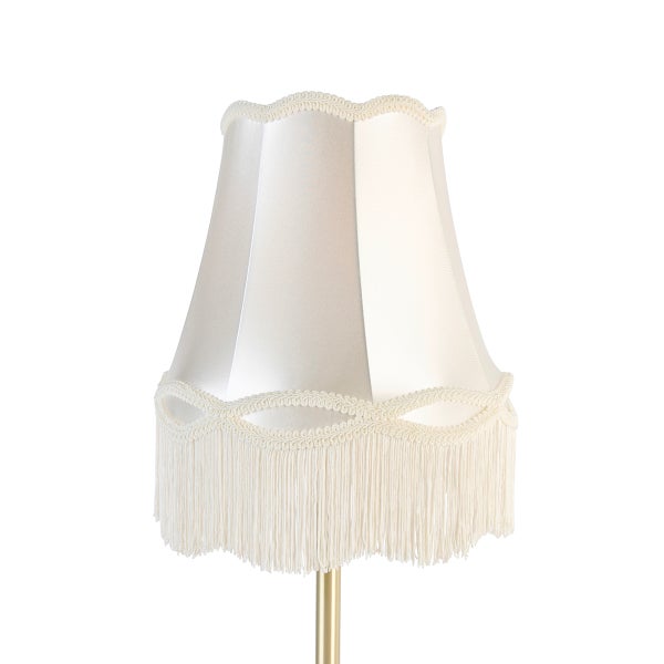Lampenschirm aus cremefarbenem Stoff mit dekorativer Wellenborte und langen Fransen.