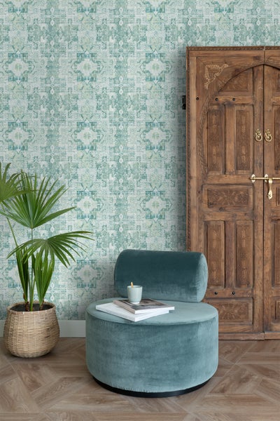 Raumansicht mit gemusterter Tapete, Sessel, Zimmerpflanze und Holztür