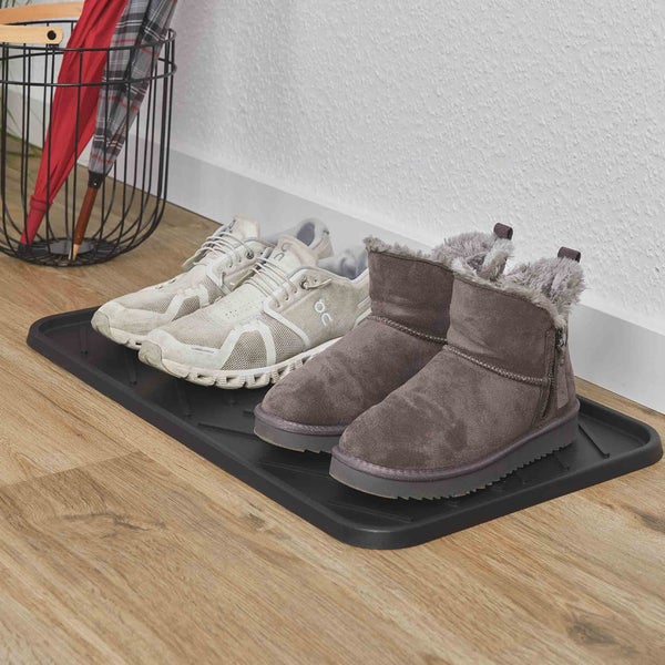 Schuhabtropfschale aus Kunststoff im hellen Eingangsbereich mit Schuhen und Stiefeln auf einem Boden in Holzoptik neben einem Metallkorb.