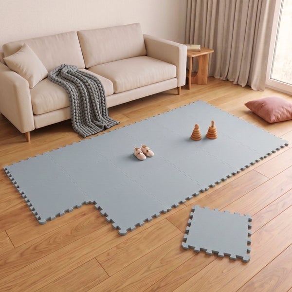 Spielmatte aus Schaumstoff in Puzzleoptik auf Holzboden im Wohnzimmer, Kinderspielbereich mit Bodenmatten zur sicheren Dämpfung.