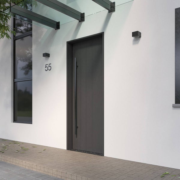 Moderne Haustür in Anthrazit mit langem Stoßgriff, weißer Fassade, Vordach aus Glas und Außenleuchten.