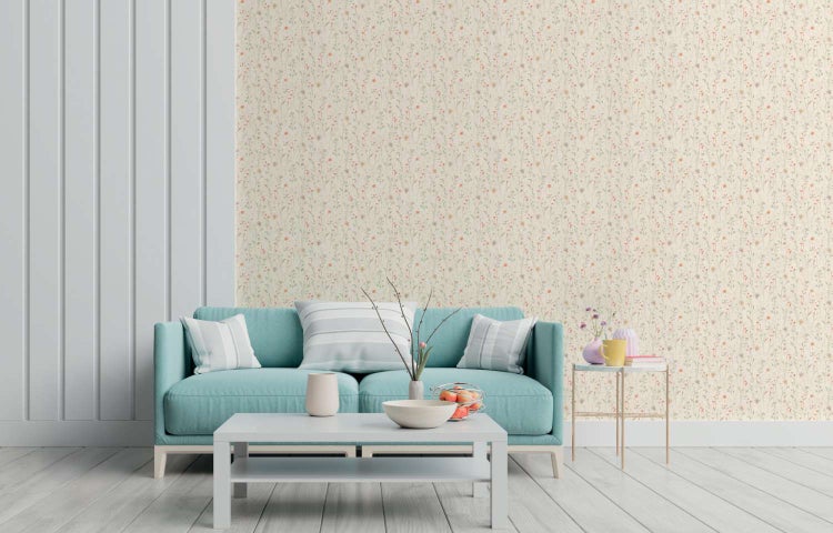 Wohnzimmer mit Vliestapete mit floralem Blumenmuster, davor ein Sofa, ein Couchtisch und Beistelltisch mit Dekorationsartikeln.