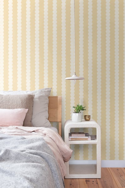 Schlafzimmer mit Bett, Nachttisch, Lampe und Tapete mit Punktmuster