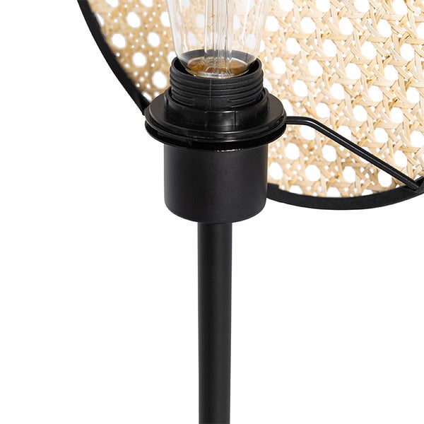 Detailaufnahme einer Stehlampe mit Lampenschirm aus Rattan und einem schwarzen Metallfuß.