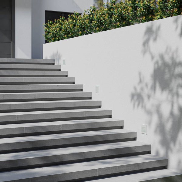 Moderne Außentreppe mit Betonstufen und rechteckigen Wandeinbauleuchten in einer weißen Seitenwand.