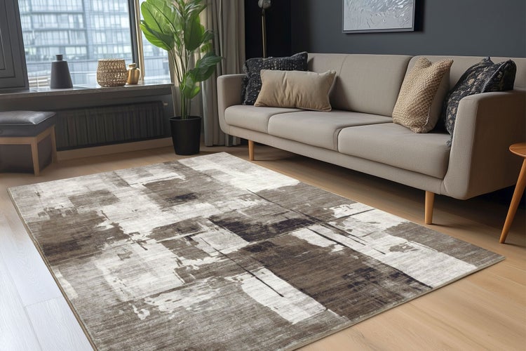 Moderner Wohnzimmerteppich mit abstraktem Muster in einem hellen, wohnlich eingerichteten Raum mit Sofa und Zimmerpflanze.