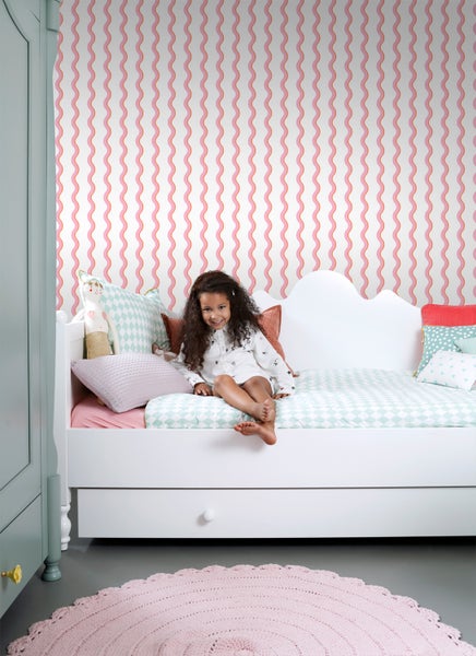 Mädchenzimmer mit weißem Tagesbett, gemusterten Kissen und gewellter Tapete