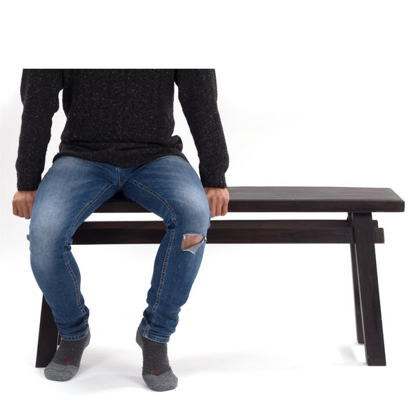 Person sitzt auf einer dunklen Holzbank.