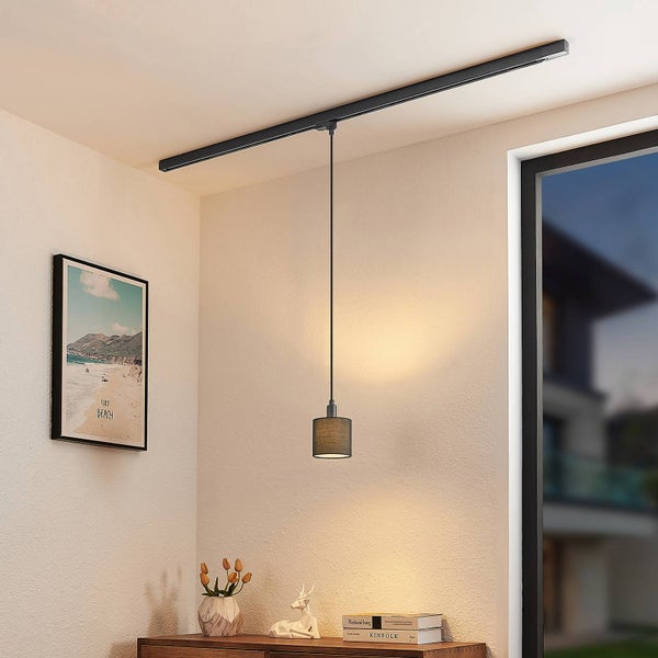 Modernes Schienensystem aus Metall in Schwarz an der Decke montiert mit einer Pendelleuchte über einer Holzkommode in einem hellen Raum.