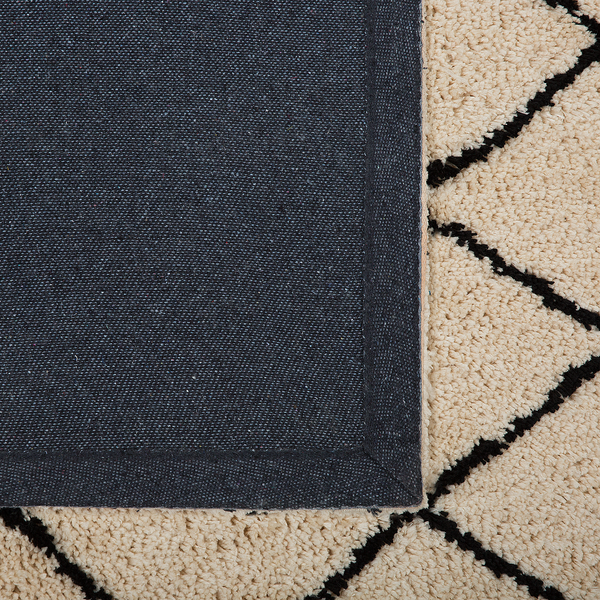 Detailansicht eines Hochflor-Teppichs mit Rautenmuster und strapazierfähiger Textilrückseite.