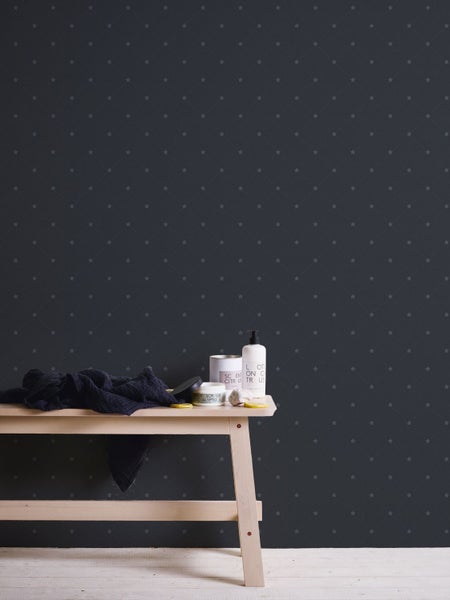 Raumansicht mit dunkel gemusterter Tapete, Holzbänkchen mit Kosmetikprodukten und Handtuch