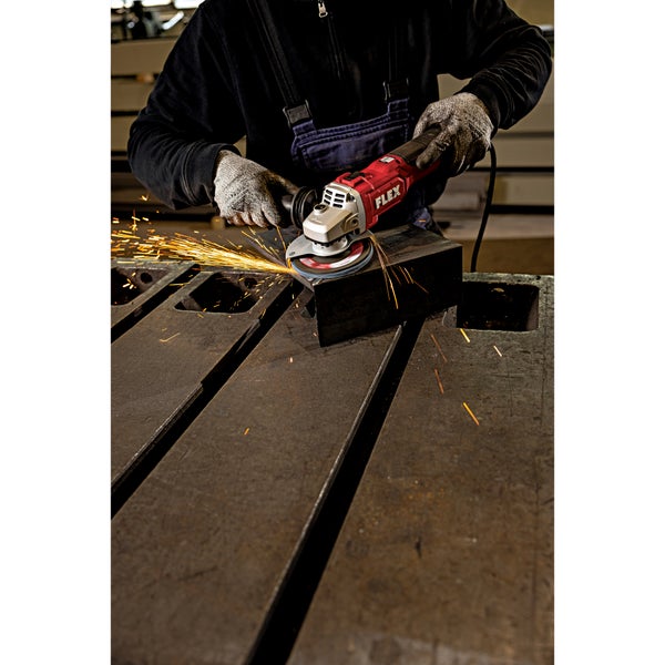 Handwerker schleift mit einem kabelgebundenen Flex Winkelschleifer Metall auf einem Arbeitstisch mit Funkenflug.