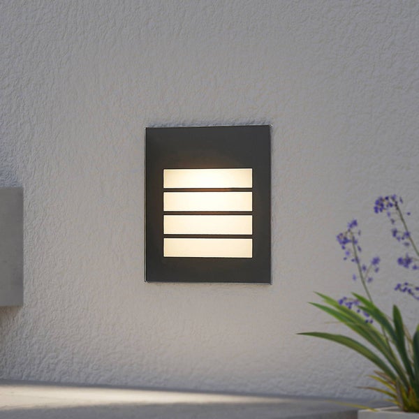Rechteckige LED-Außenwandleuchte in Anthrazit mit vier horizontalen Lichtauslässen, montiert an einer verputzten Außenwand.
