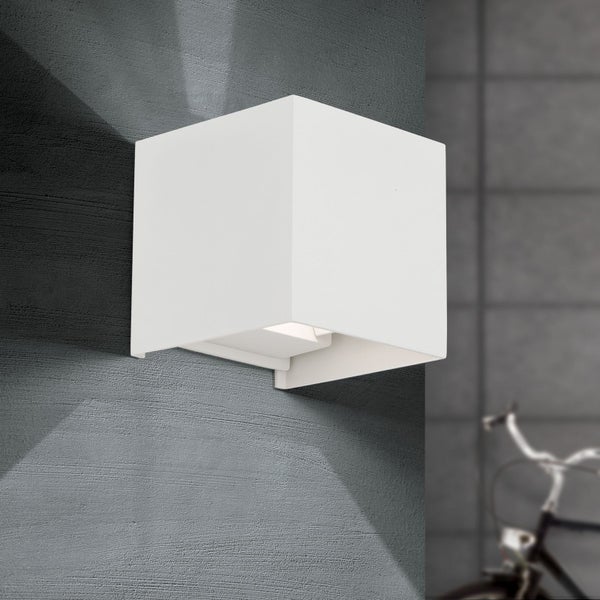 Würfelförmige Außenwandleuchte in Weiß mit Lichtkegel nach oben und unten an einer grauen Hauswand.