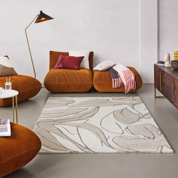 Modernes Wohnzimmer mit abstrakt gemustertem Teppich, orangefarbenen Cord-Sitzmodulen, goldfarbener Stehlampe und Sideboard aus dunklem Holz.