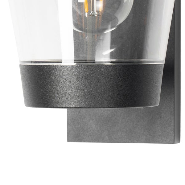 Nahaufnahme einer Außenwandleuchte mit klarem Glasschirm, anthrazitfarbenem Metallsockel und sichtbarem Leuchtmittel.