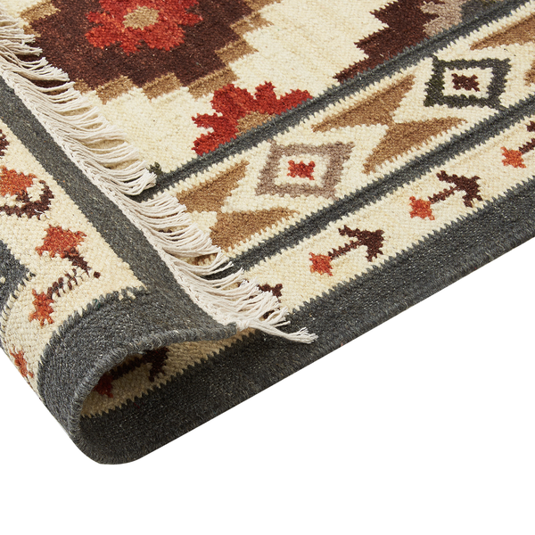 Gewebter Teppich mit Fransen und ethnischem Muster in Beige, Braun und Rot.