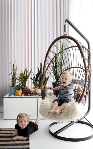 Einrichtungsidee mit Hängekorb, Kommode, Pflanzen und zwei Kindern in einem hellen Raum.