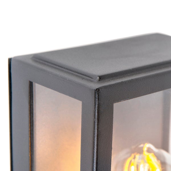 Detailaufnahme einer schwarzen Außenwandleuchte aus Metall und Glas mit eingeschaltetem Leuchtmittel.