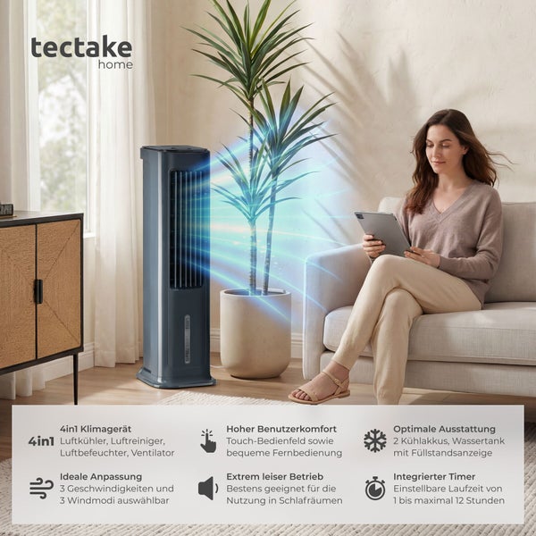 Modernes tectake 4 in 1 Klimagerät in einem hellen Wohnzimmer neben einer Zimmerpflanze und einer Person, die auf einem Sofa ein Tablet nutzt.