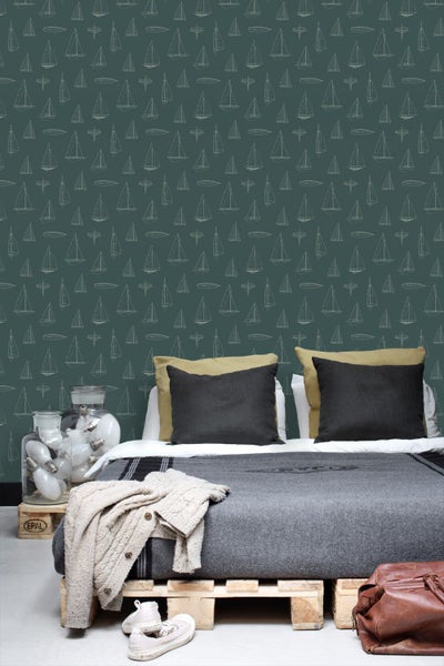 Tapete mit Segelboot-Muster in einem Schlafzimmer mit Palettenbett, Kissen und Glasbehältern mit Glühbirnen.