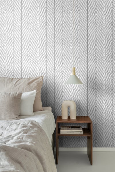 Schlafzimmer mit Bett, Nachttisch und Tapete mit Winkelmuster