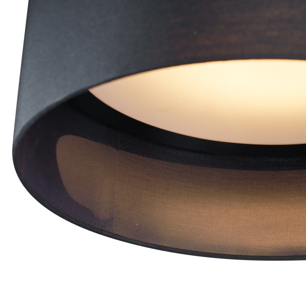 Nahaufnahme eines zylindrischen Lampenschirms aus Stoff mit dunkler Außenseite und goldfarben glänzender Innenseite.