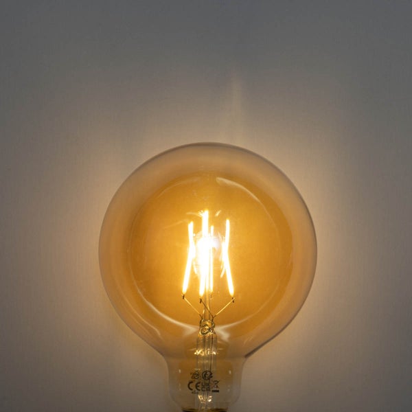 Eingeschaltete LED-Filament-Globelampe mit warmem Licht und sichtbaren Leuchtfäden.