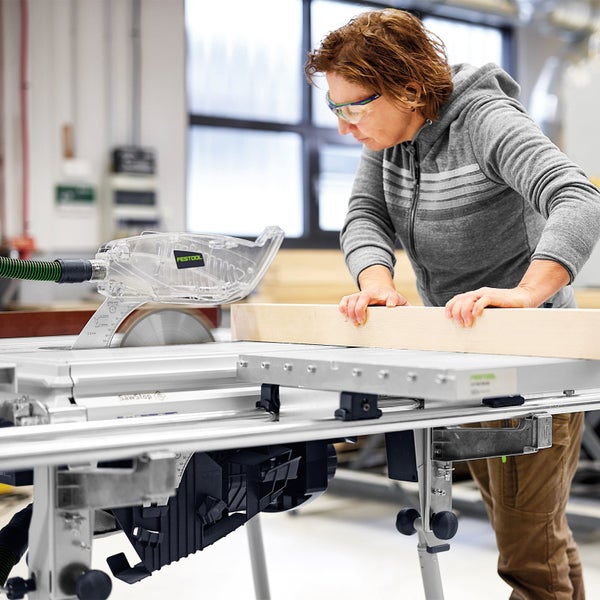 Eine Frau arbeitet mit einer Festool Tischkreissäge SawStop in einer Werkstatt und führt einen Holzbalken durch das Sägeblatt; Festool Logo.
