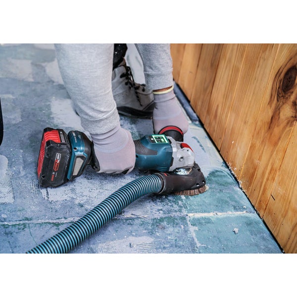 Eine Person verwendet einen Akku-Winkelschleifer mit Staubsaugeranschluss auf einer Oberfläche.