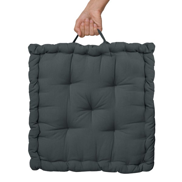 Eine Hand hält ein quadratisches, gestepptes Sitzkissen