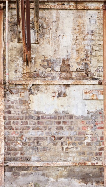 Backsteinmauer mit Putz und Rohren