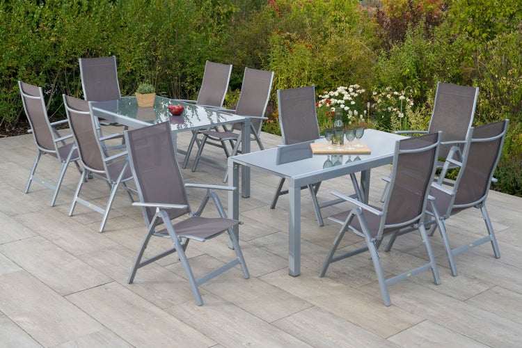 Szene mit zwei Gartentischen aus Glas und zehn Gartenstühlen auf einer Terrasse