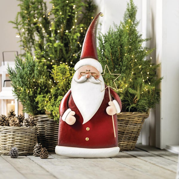 Weihnachtsmann Dekofigur aus Metall mit Stern, platziert vor beleuchteten Tannen in Weidenkörben für eine festliche Weihnachtsdekoration.