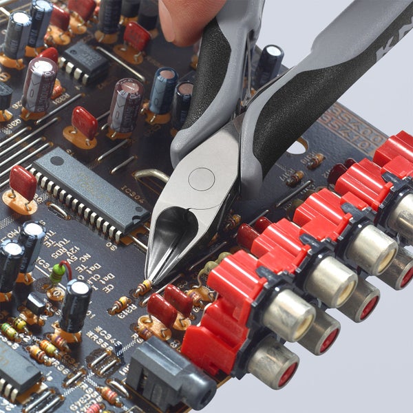 Elektronikzange schneidet Bauteil auf einer Platine