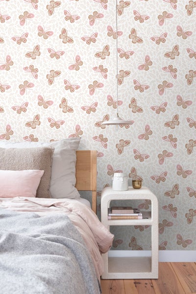 Schlafzimmer mit Bett und Nachttisch vor Tapete mit Schmetterlingsmuster