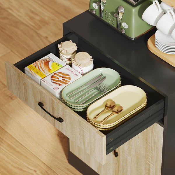 Geöffnete Küchenschublade in einem grauen Schrank mit Holzfront, gefüllt mit Backmischungen, Gläsern, Tellern und Besteck.